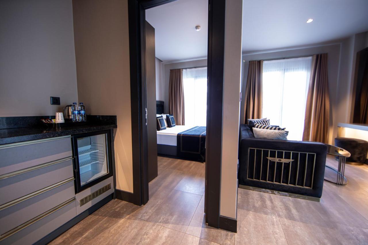 Menalo Hotel Premium Istanbul Airport Exterior photo The photo shows an interior space that appears to be a modern hotel suite or apartment. On the left, there's a small kitchenette area featuring a refrigerator and possibly coffee-making facilities, with a sleek countertop. The entrance leads to a liv