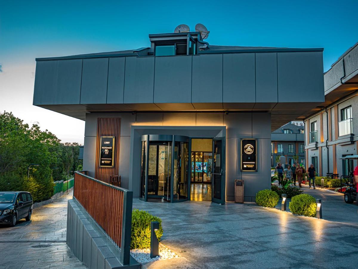 Menalo Hotel Premium Istanbul Airport Exterior photo The photo shows a modern building, likely a commercial establishment such as a restaurant or hotel. The architecture features a sleek, minimalist design with a flat roof and large glass doors at the entrance. The exterior is primarily finished in gra