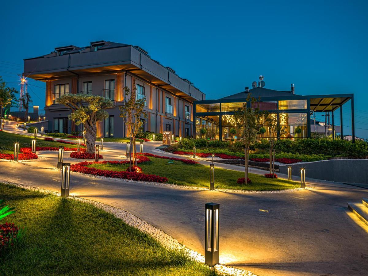 Menalo Hotel Premium Istanbul Airport Exterior photo The photo shows a beautifully designed modern building set in a landscaped area during twilight. There are illuminated pathways leading up to the structure, which features stylish architecture with large windows. Surrounding the building are well-mai
