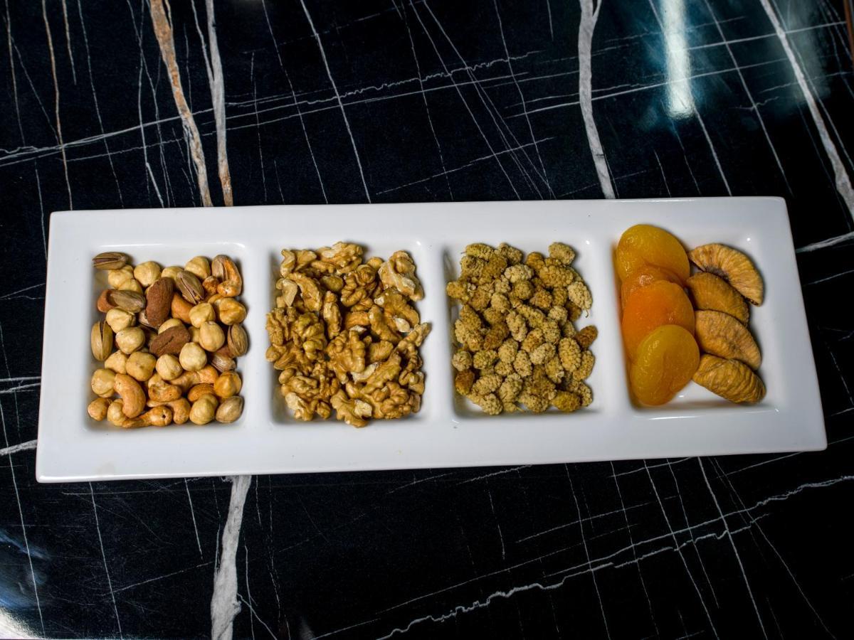 Menalo Hotel Premium Istanbul Airport Exterior photo The photo shows a rectangular white plate divided into four sections, each containing different types of snacks. 

1. **First section**: A mix of various nuts, including cashews and possibly almonds.
2. **Second section**: Walnuts, which have a disti