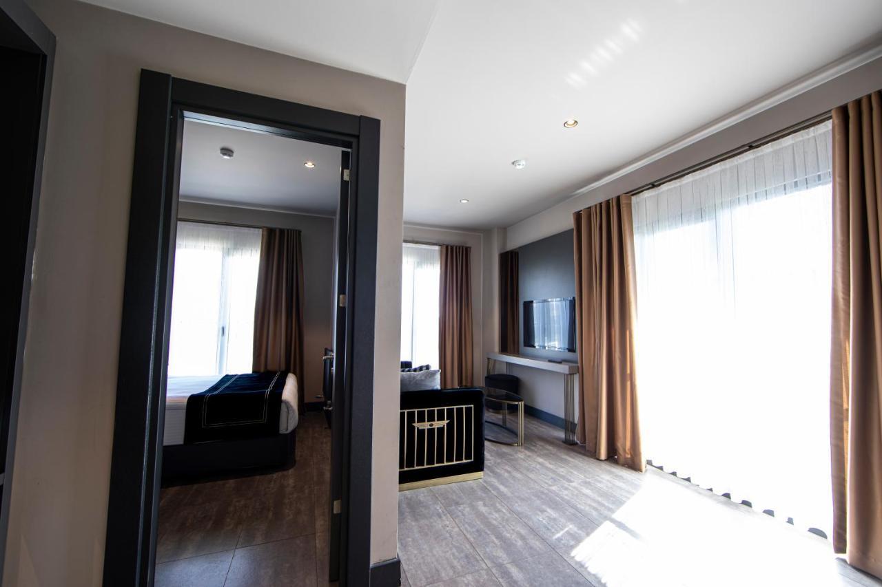 Menalo Hotel Premium Istanbul Airport Exterior photo The photo shows an interior space, likely a hotel room or suite. On the left, there is a doorway leading to another area, and across from it, large windows with light-colored curtains allow natural light to enter the room. 

The room features a cozy 