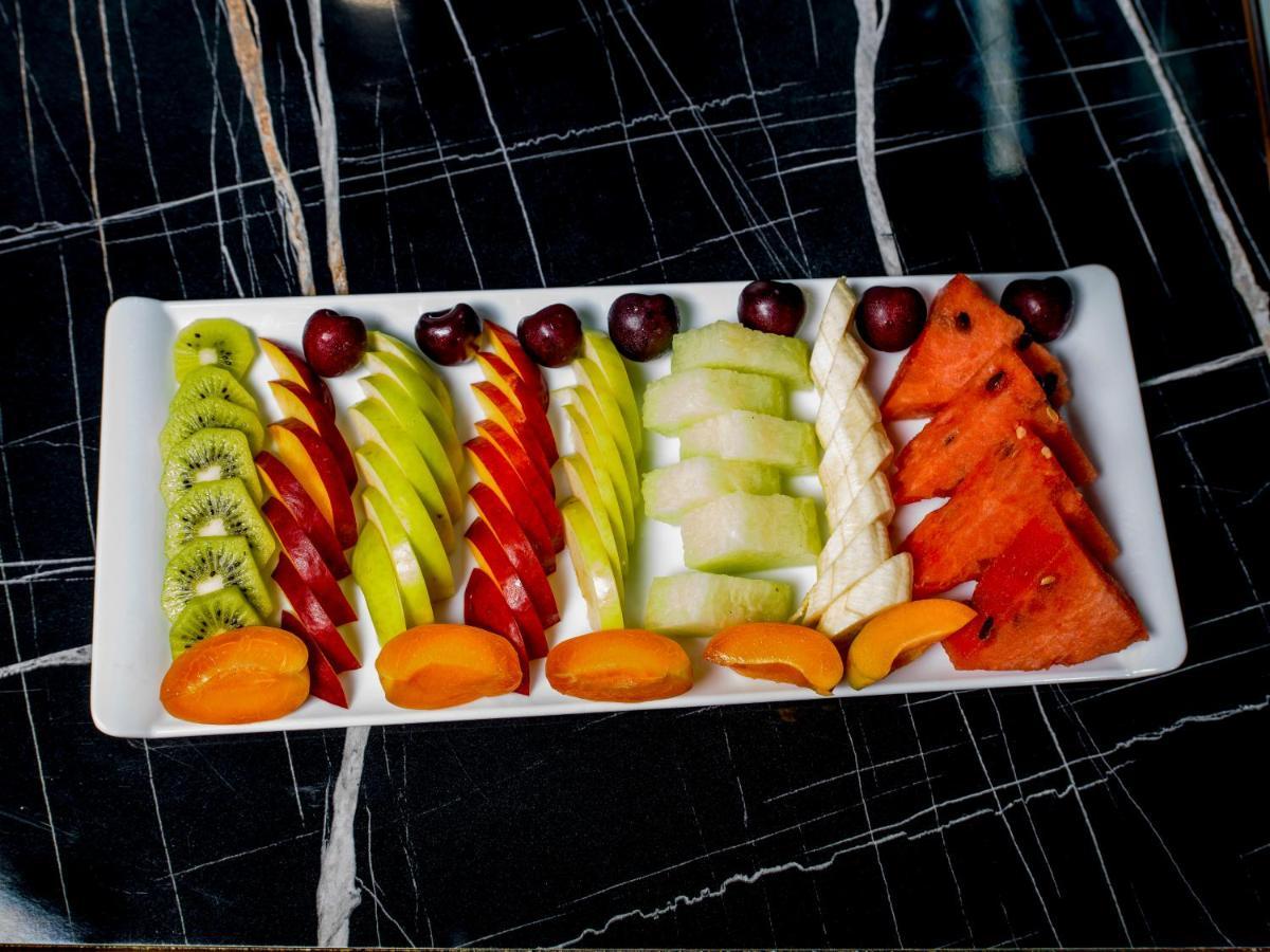 Menalo Hotel Premium Istanbul Airport Exterior photo The photo shows a beautifully arranged platter of various fruits. The fruits are cut into decorative shapes and displayed in rows. From left to right, the platter features:

- Slices of kiwi
- Spiraled cuts of green apple
- Red apple slices
- Pieces 