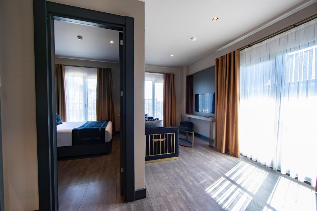 Menalo Hotel Premium Istanbul Airport Exterior photo The photo shows a modern hotel room set up. In the foreground, there is an entrance leading to the room, with a view of a second room through an open door. The interior features large windows with sheer curtains allowing natural light to fill the spa