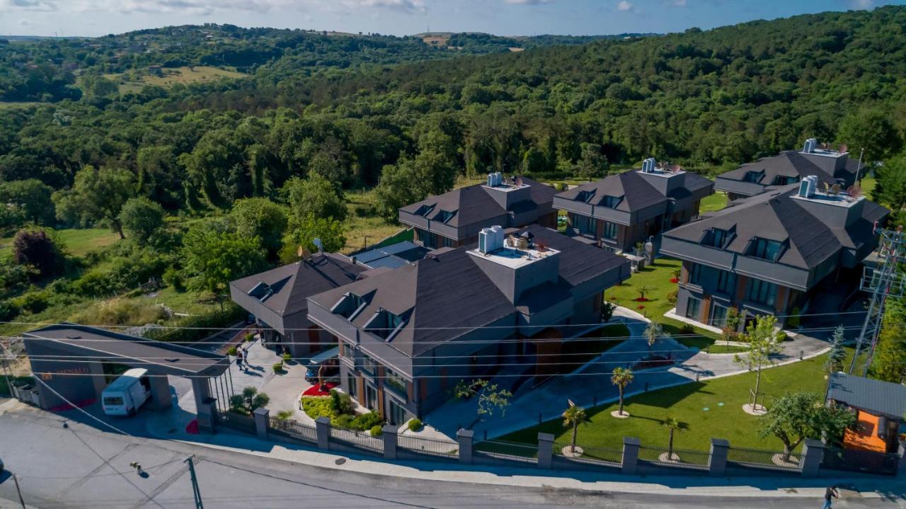 Menalo Hotel Premium Istanbul Airport Exterior photo The photo shows an aerial view of a luxurious residential area featuring several large houses. The homes have a modern design with dark roofs and large windows. They are surrounded by well-maintained gardens and lawns, with trees and greenery visible
